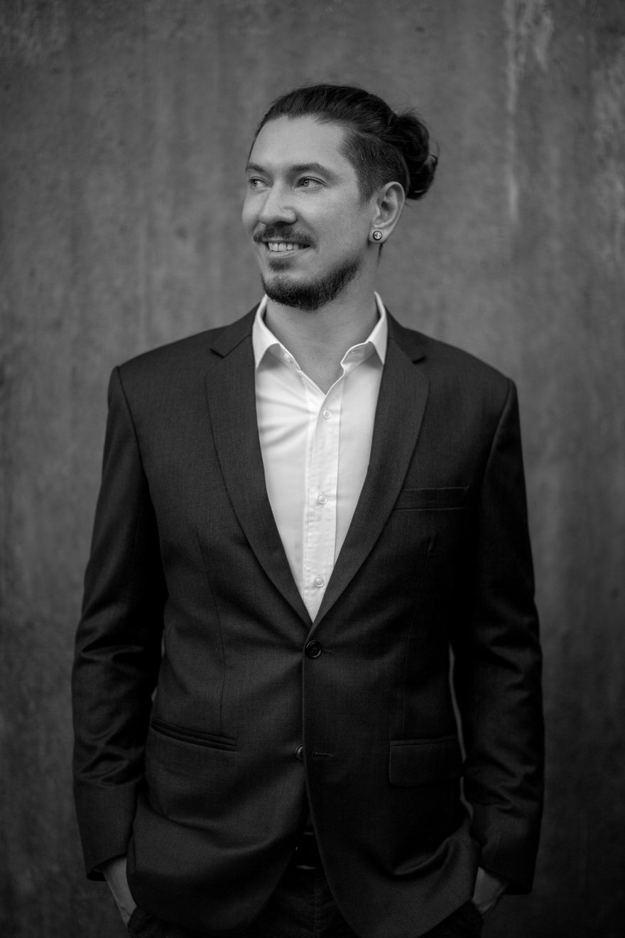 Petja Klass, black-and-white portrait against a concrete wall